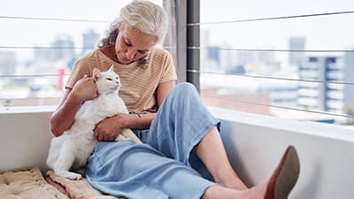 Senior woman cuddling with her cat while relaxing on the balcony at home