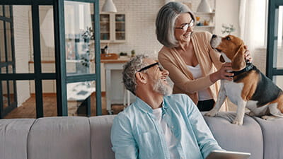 A senior couple laughing with their pet dog at home