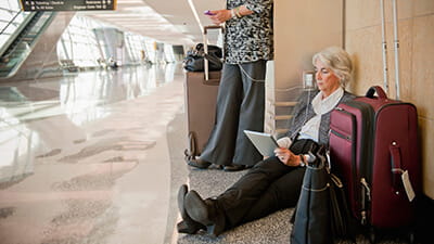 Businesswomen at an airport between flights using a plug socket to charge their devices