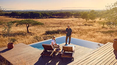 A mature couple relaxing by the pool at a safari retreat in South Africa.