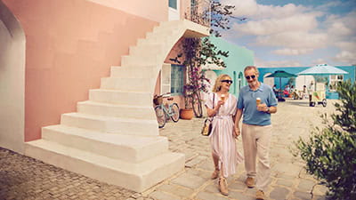 A mature couple walking hand in hand eating ice cream as they take a leisurely stroll on holiday.