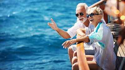 Closeup side view of mid 60's couple enjoying a sailing cruise during summer vacation at seaside.