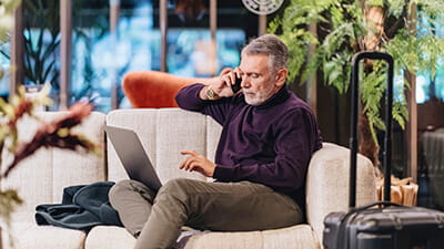 Mature man talking on mobile phone while sitting at hotel lobby