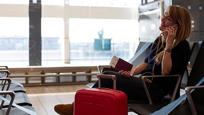 A mature woman on the phone sitting in an airport departure lounge