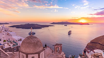 Aerial shot of a cruise ship passing by a shore line at sunset