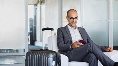 Mature man using mobile phone at the airport in the lounge area.