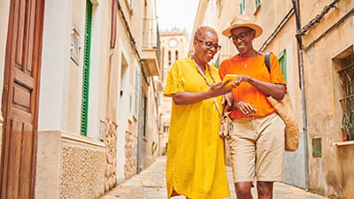 Two mature women walking together exploring an old town in Europe.
