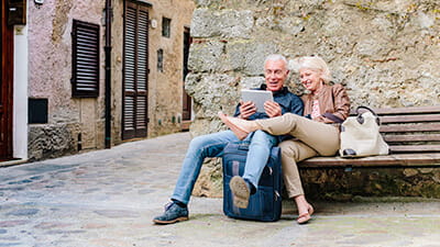 Tourist couple sitting on bench looking at digital tablet in Siena, Tuscany, Italy