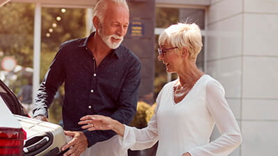 A mature couple packing luggage in their car at a hotel