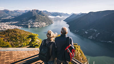 Mature couple hike above lake Lugano in the morning