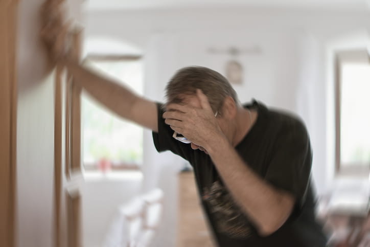 A man with his hand on his head trying to support himself as he suffers a stroke