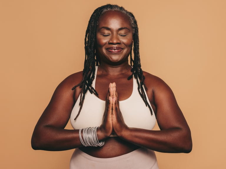 An older woman meditating in a yoga pose | Getty