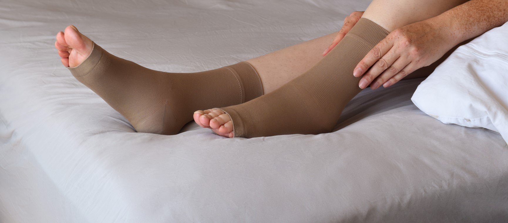 A close up of a woman putting compression socks on to help varicose veins | Shutterstock
