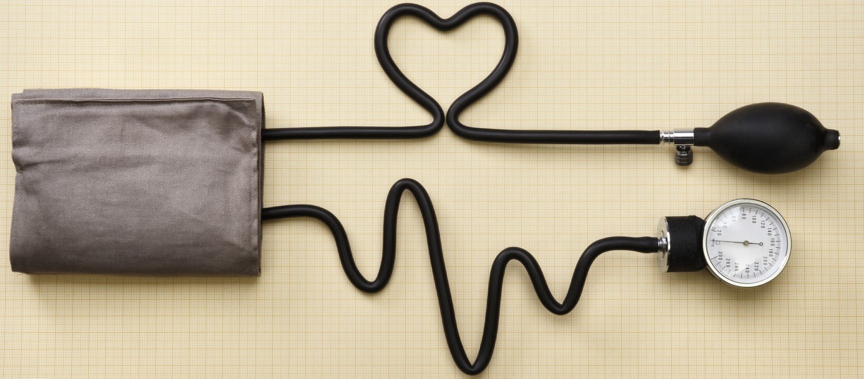 A blood pressure monitor with the tubes shaped to look like a heart and a heartbeat line | Getty