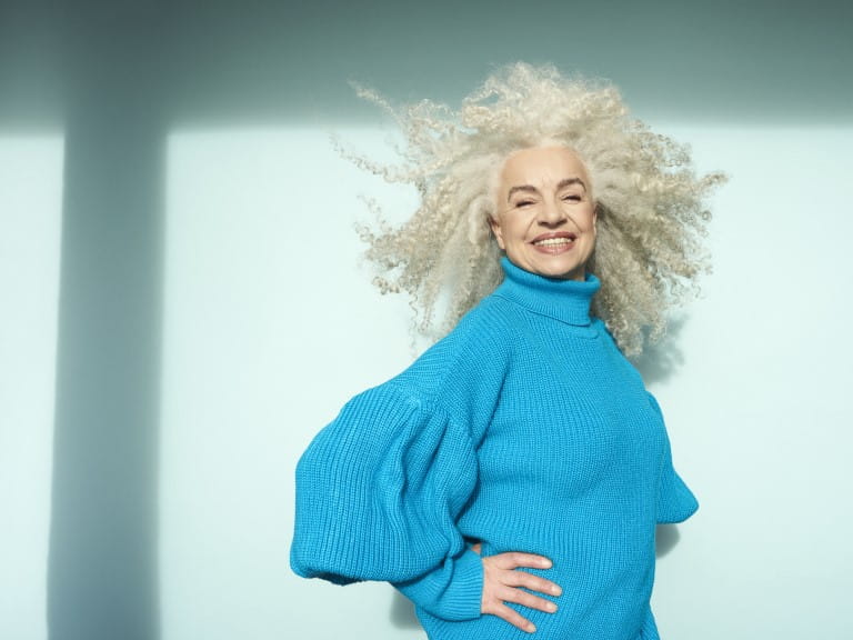 A joyful woman with long beautiful white-grey curls | Getty