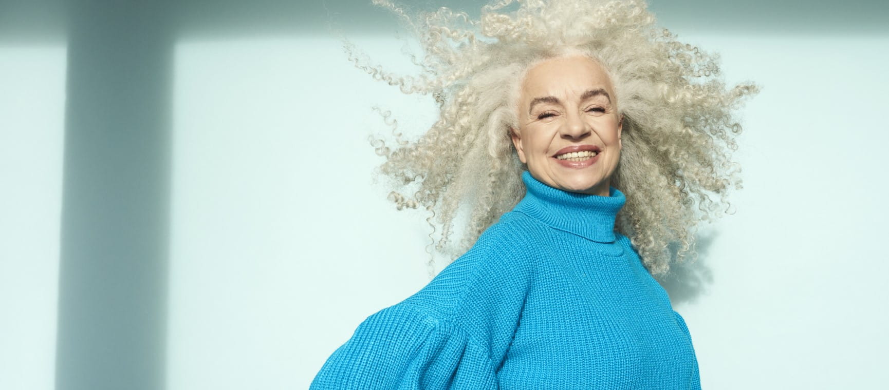 A joyful woman with long beautiful white-grey curls | Getty