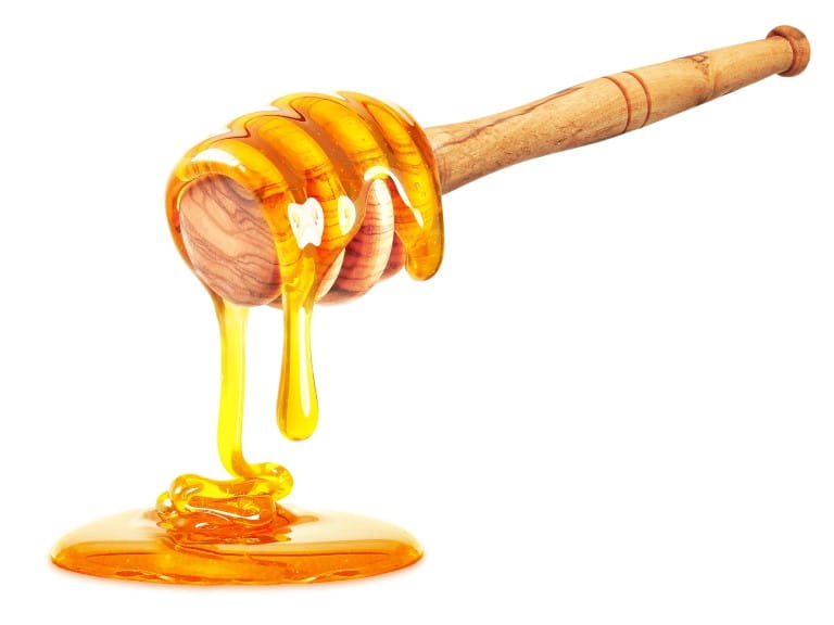 A wooden honey dipper dripping with honey to represent an alternative to sugar | Shutterstock