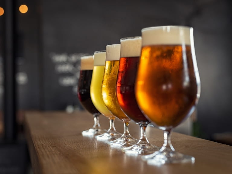 A row of beer glasses on a bar containing beers of different colours