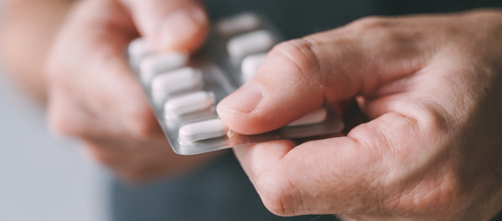 A person takes an over-the-counter painkiller | Getty/BitsAndSplits