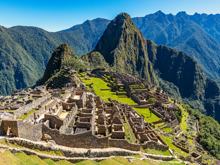 The inca ruins of the lost city Machu Picchu during daytime with tourists visiting the site near the city of Cusco, Peru, South America.