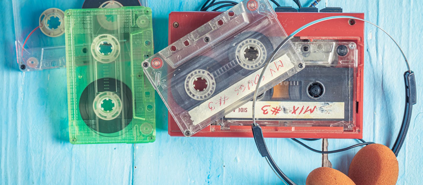 Old fashioned cassette mix tapes with a walkman and headphones on a blue background
