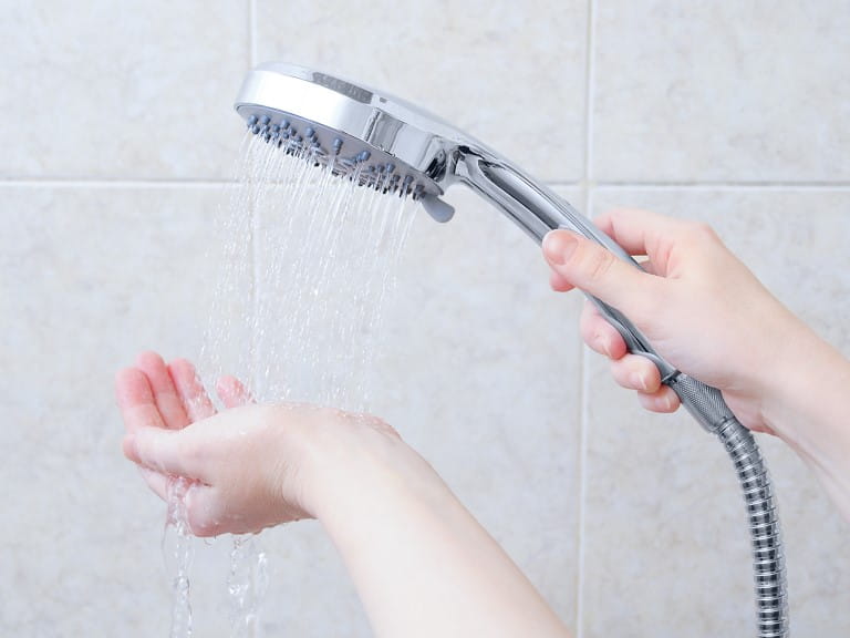 Someone holding their hand beneath a showerhead
