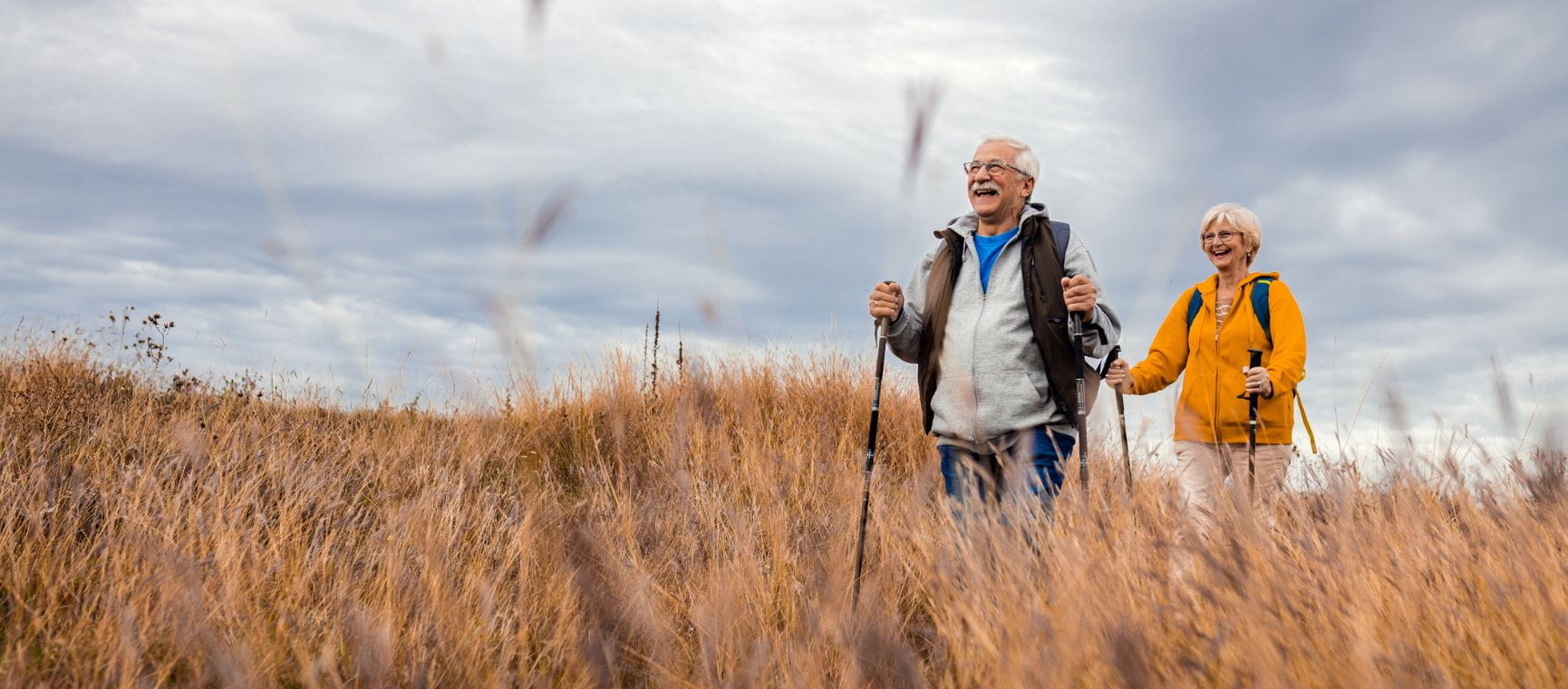 A man and woman walking through a field on an autumn day