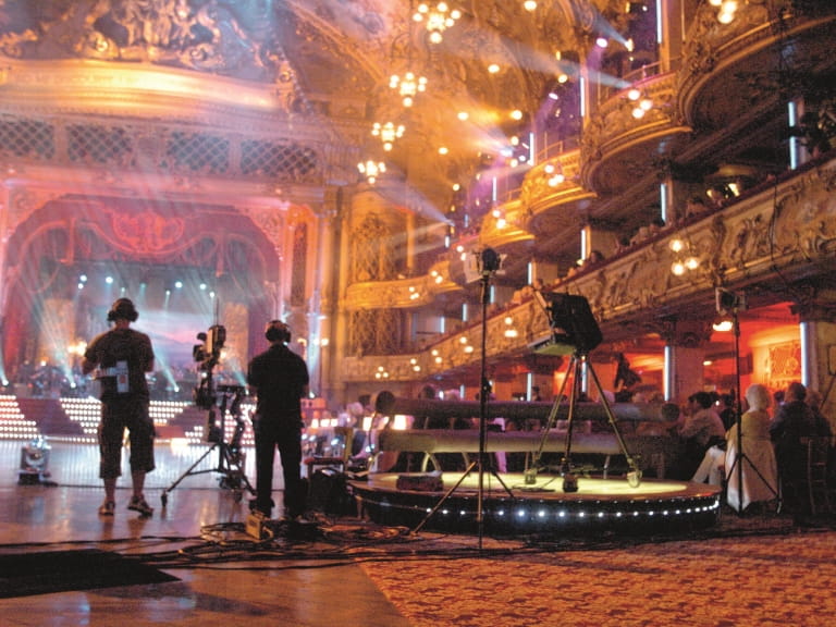 Filming 'Strictly Come Dancing' live at Blackpool Tower Ballroom; lights, cameras, crew and audience members are visible, watching the dancefloor.