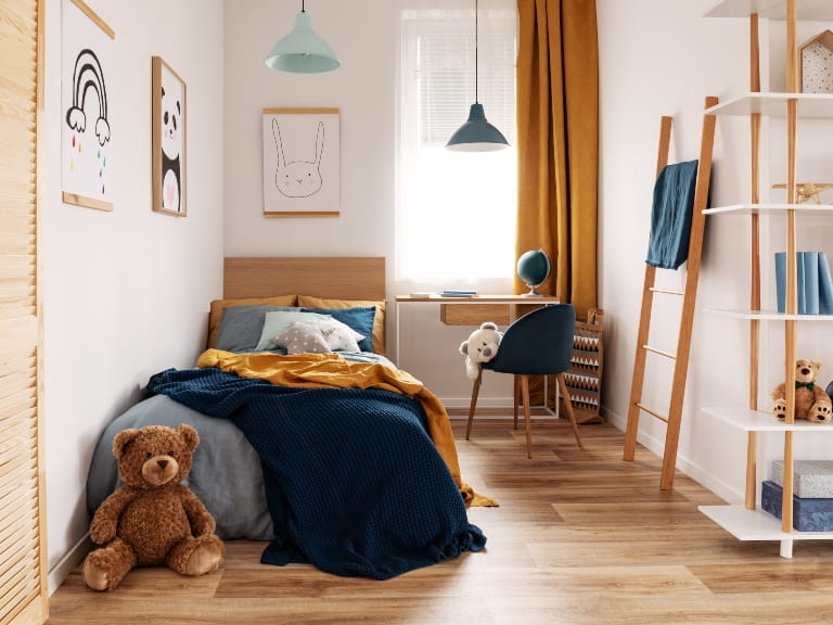 A children's bedroom with single bed, desk and shelving, with soft furnishings in shades of blue and orange