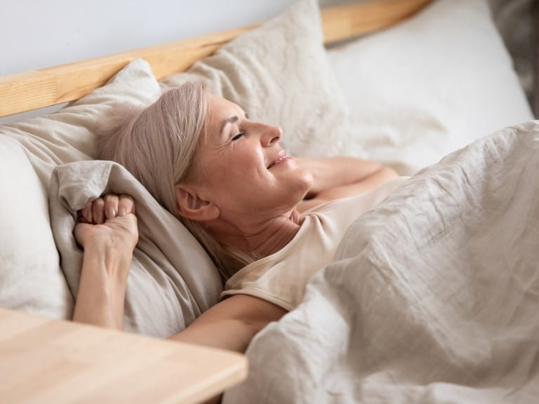 An older woman waking up in bed