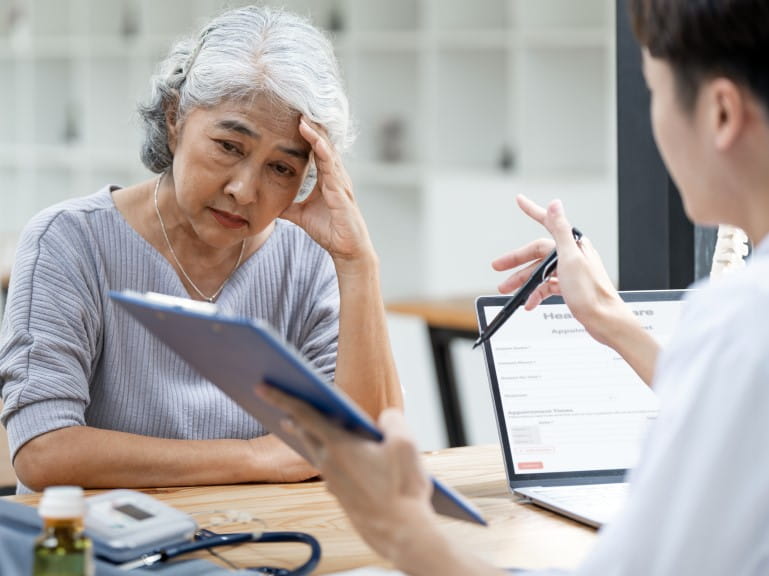 An older woman looking distressed while talking to a doctor