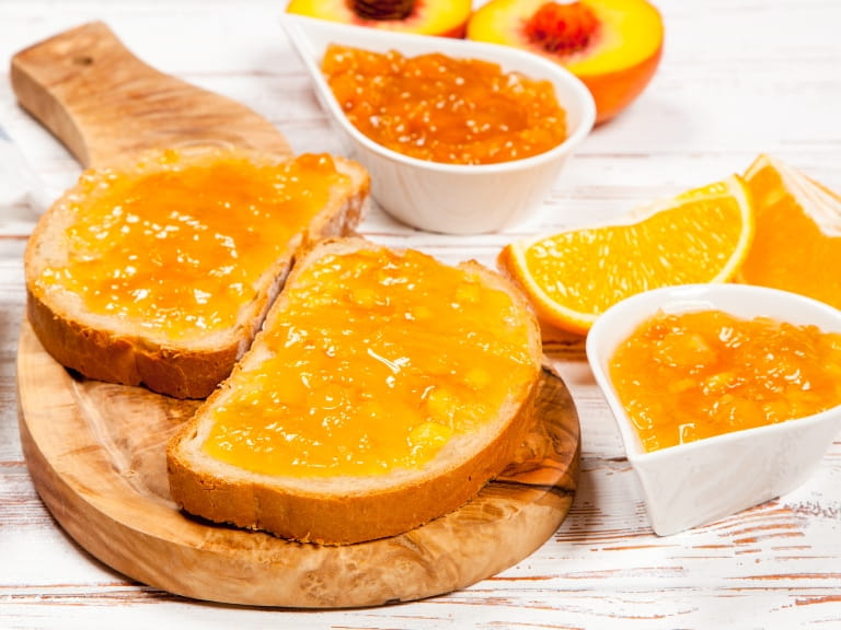 Two slices of toast topped with marmalade served on a wooden board