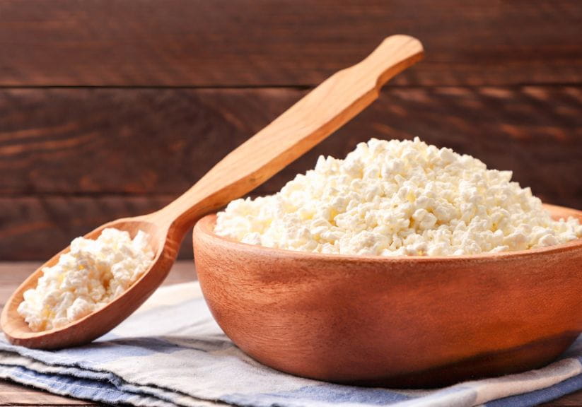 cottage cheese in a wooden bowl with a wooden spoon resting on it