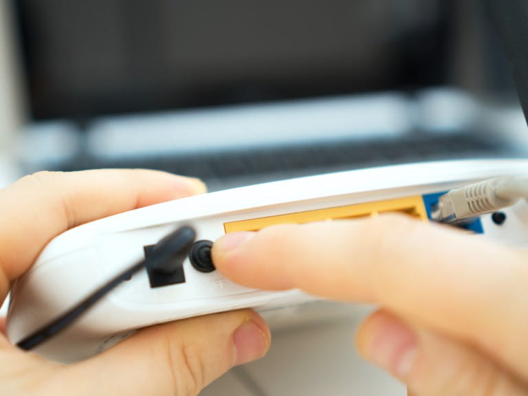 A Man pressing power button on a wifi router