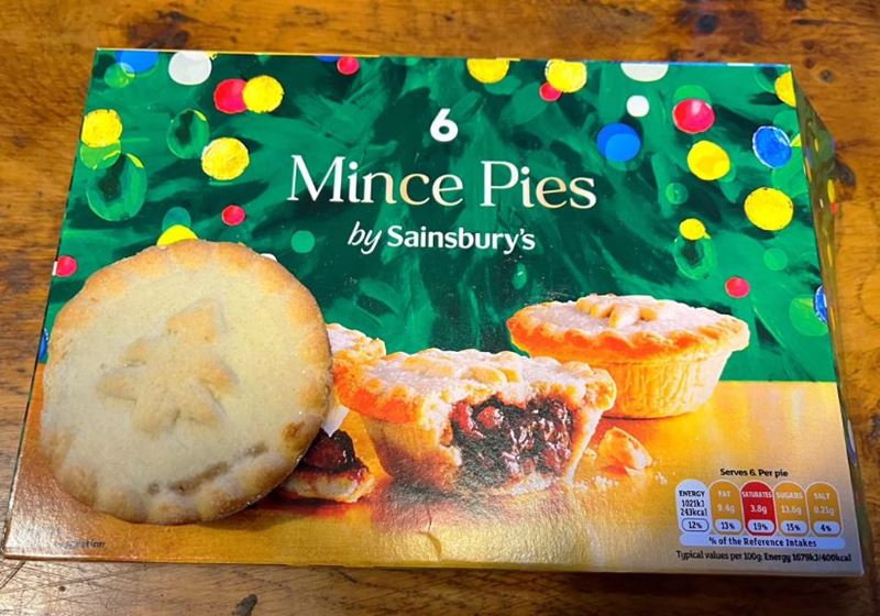 A box of Sainsbury mince pies on a wooden table