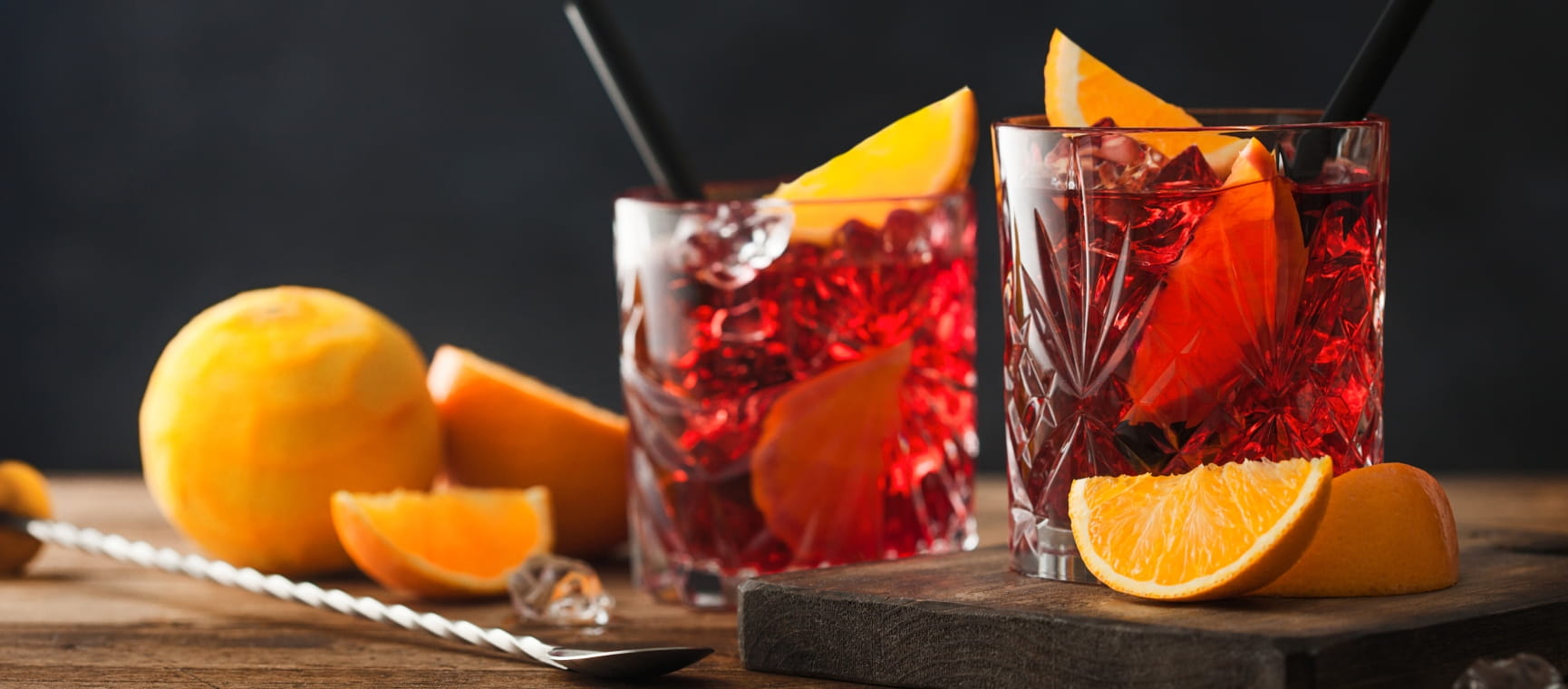 Two glasses of Negroni with fresh orange slices on the side