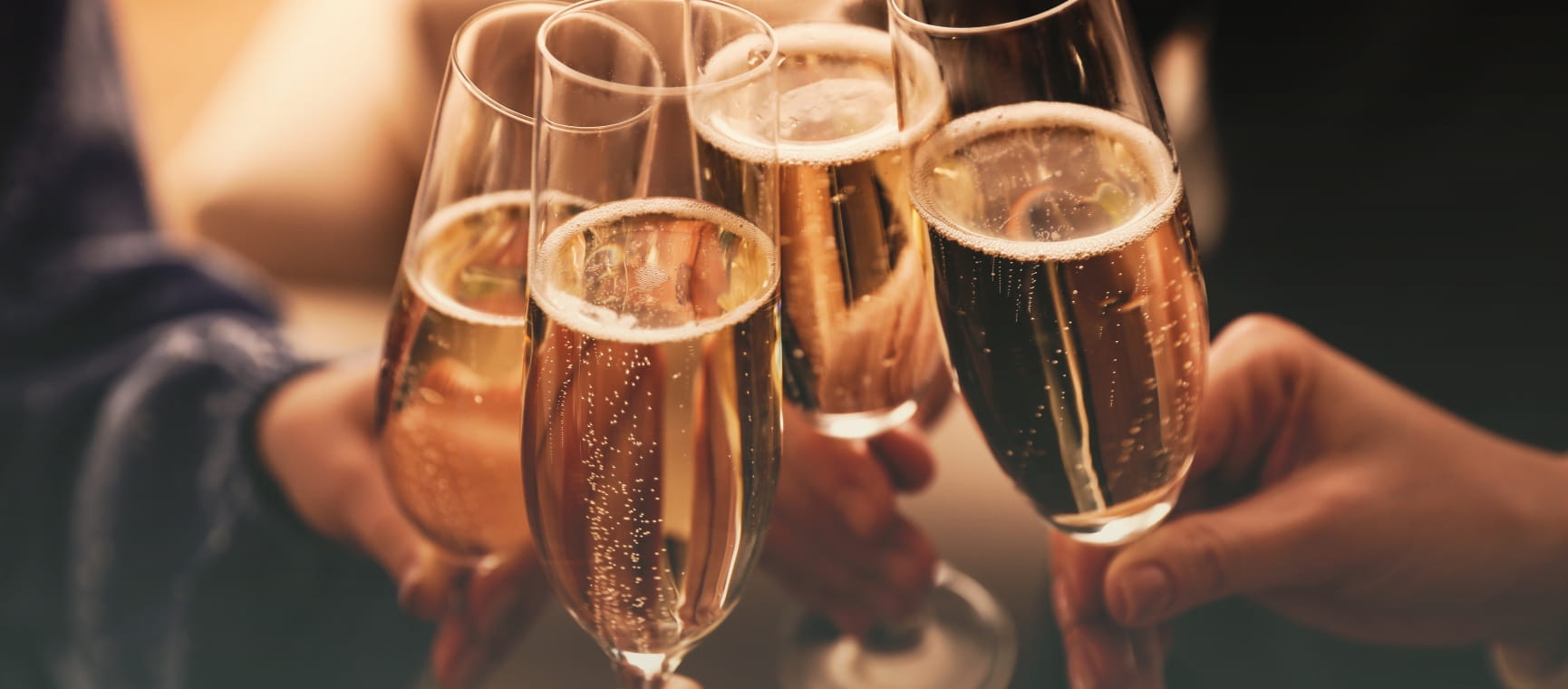 Four people clinking Champagne glasses indoors
