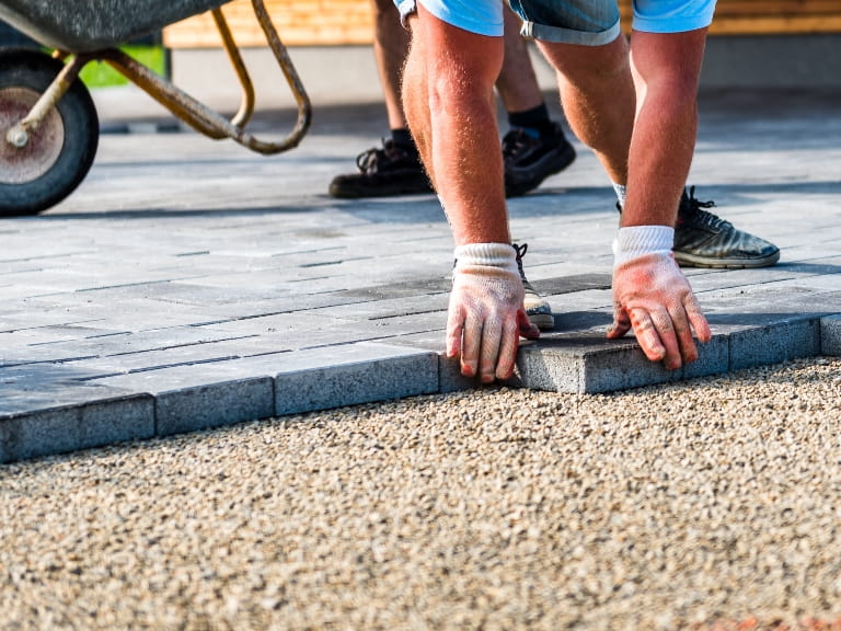 Builder laying a grey brick driveway