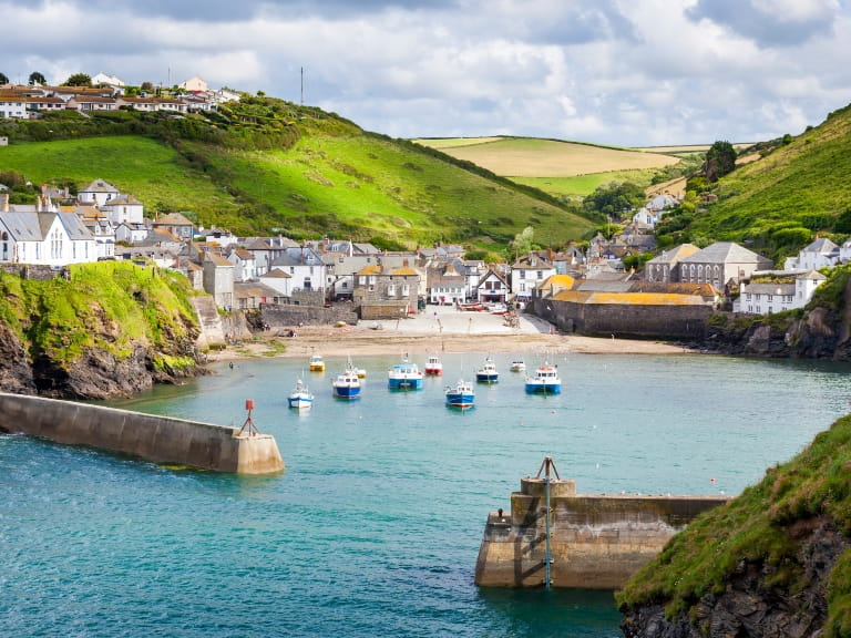 Boats in the harbour at Port Isaac, Cornwall, with views over the countryside behind the port town