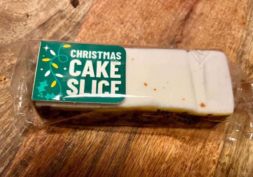 A Gregg's Christmas cake slice on a wooden board