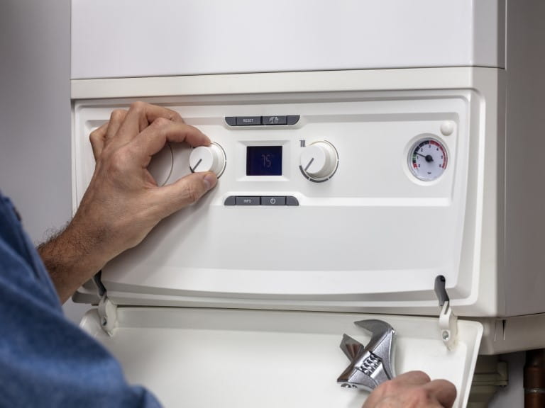 A man adjusting a dial on his boiler