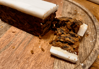 A Lidl Christmas slice with a portion cut off the end on a wood board