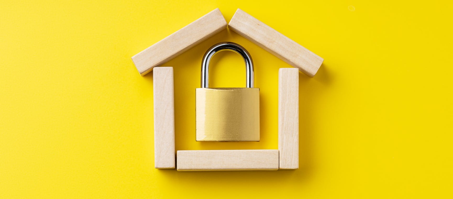 A padlock inside wooden blocks arranged in the shape of a house.