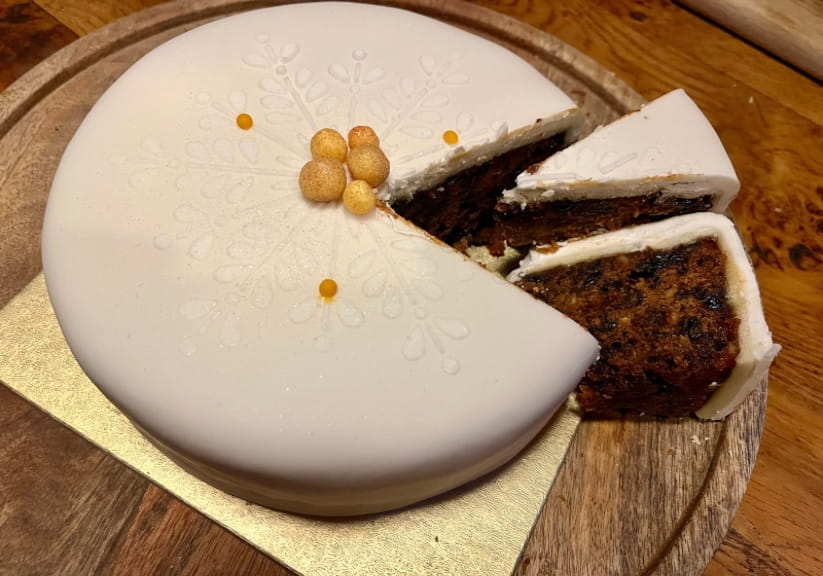 A Waitrose Christmas cake on a wood board with two slices cut ou