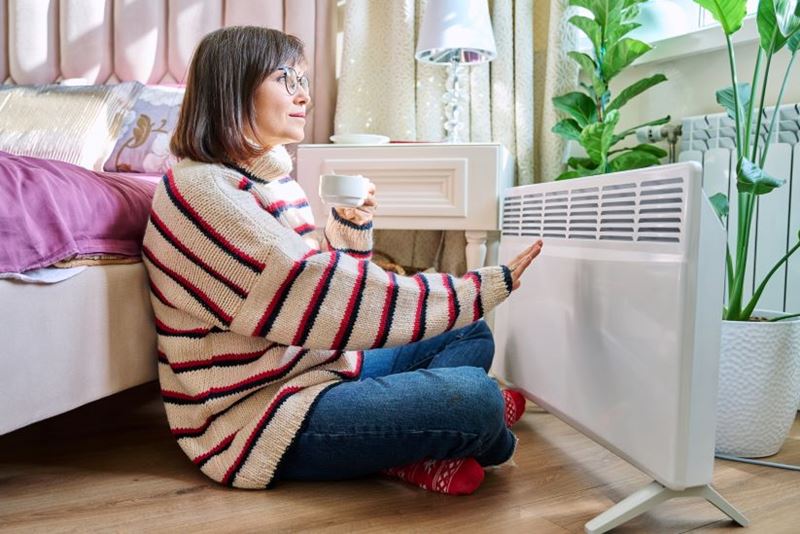 Woman huddled by an electric heater