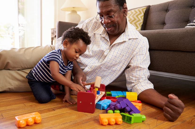 Grandpa lying on the floor playing with his son