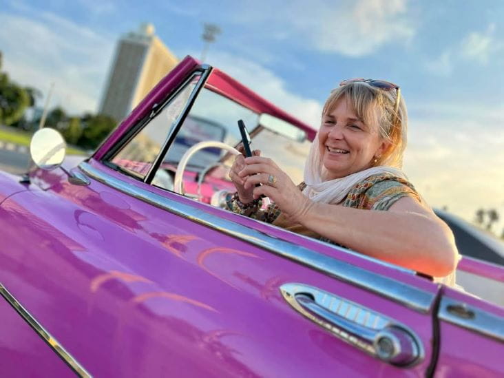Gina Cambridge in a pink car in Cuba