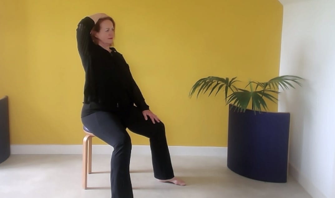Woman sat lengthening the spine