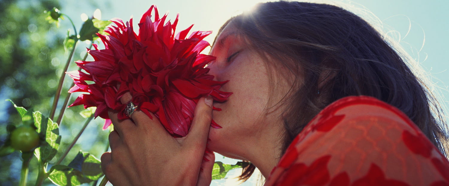 Woman sniffing a red flower