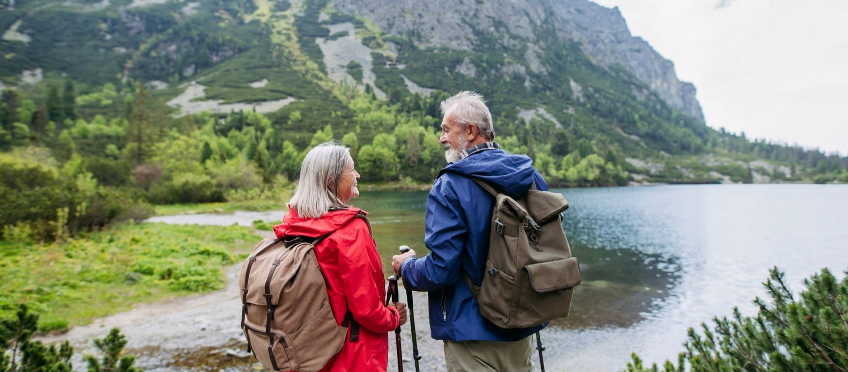 man and woman hiking with walking poles in the mountains